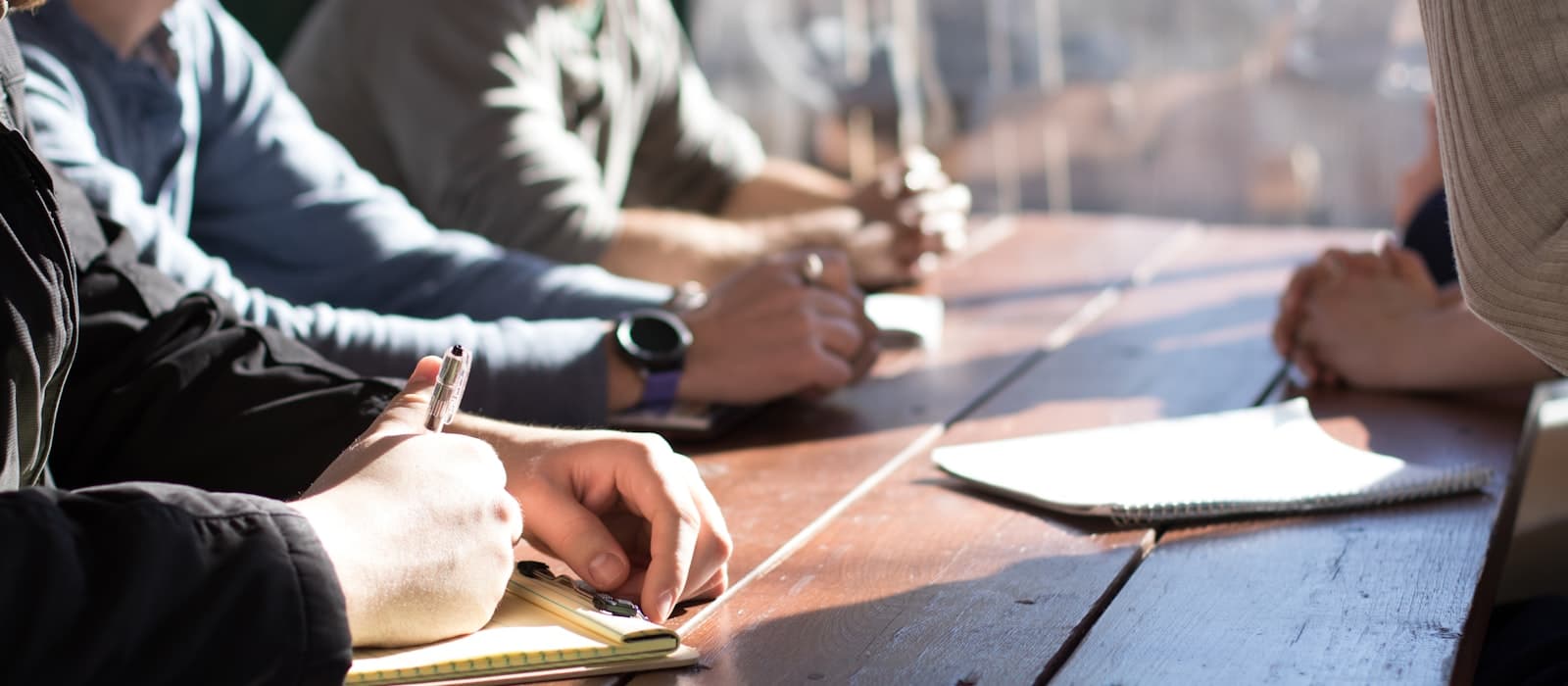 Un equipo reunido alrededor de una mesa, tomando notas durante una sesión de trabajo